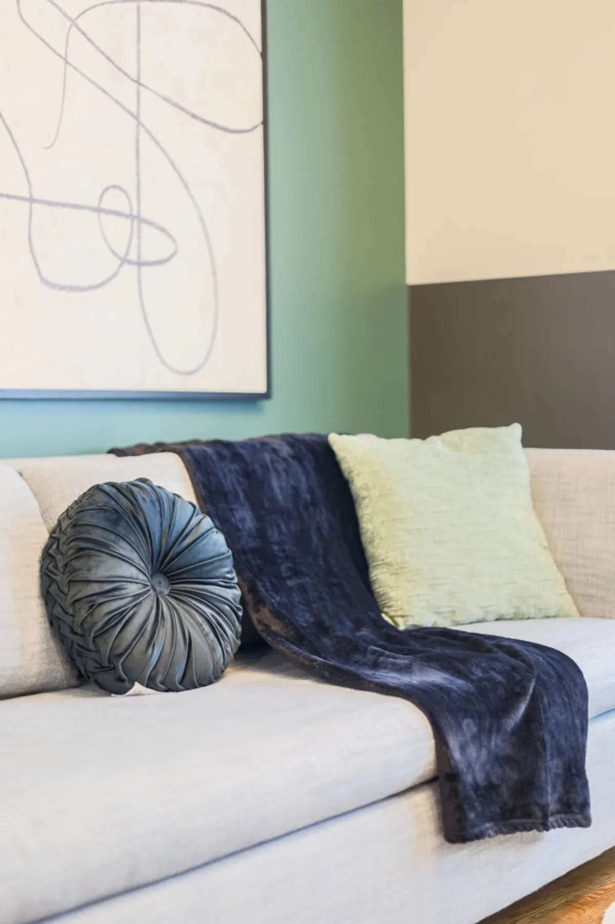 A cozy seating area featuring decorative pillows, a plush throw blanket, and wall artwork. The room radiates comfort and is well-suited for relaxing, reading, or gathering with family.