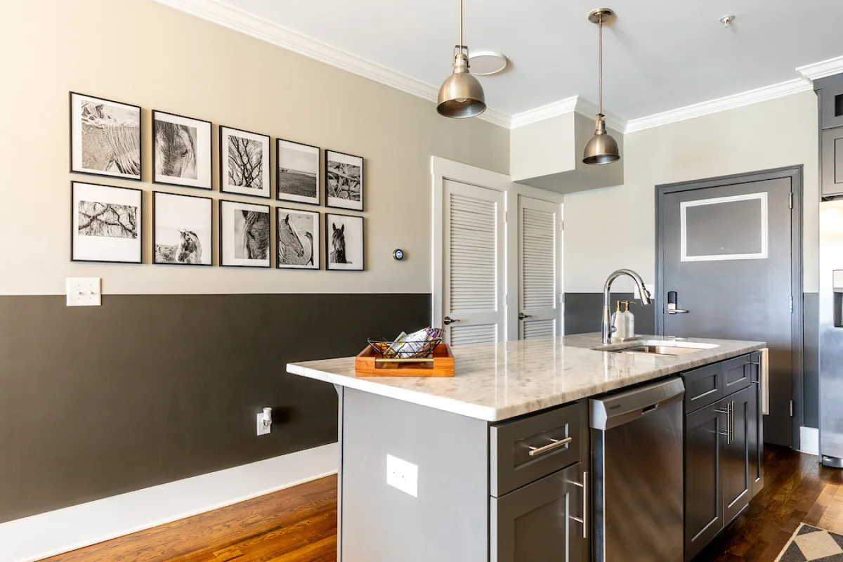 A stylish kitchen with a central island, pendant lights, and framed artwork. The space feels contemporary and open, suggesting social gatherings or quick breakfasts before a day out.