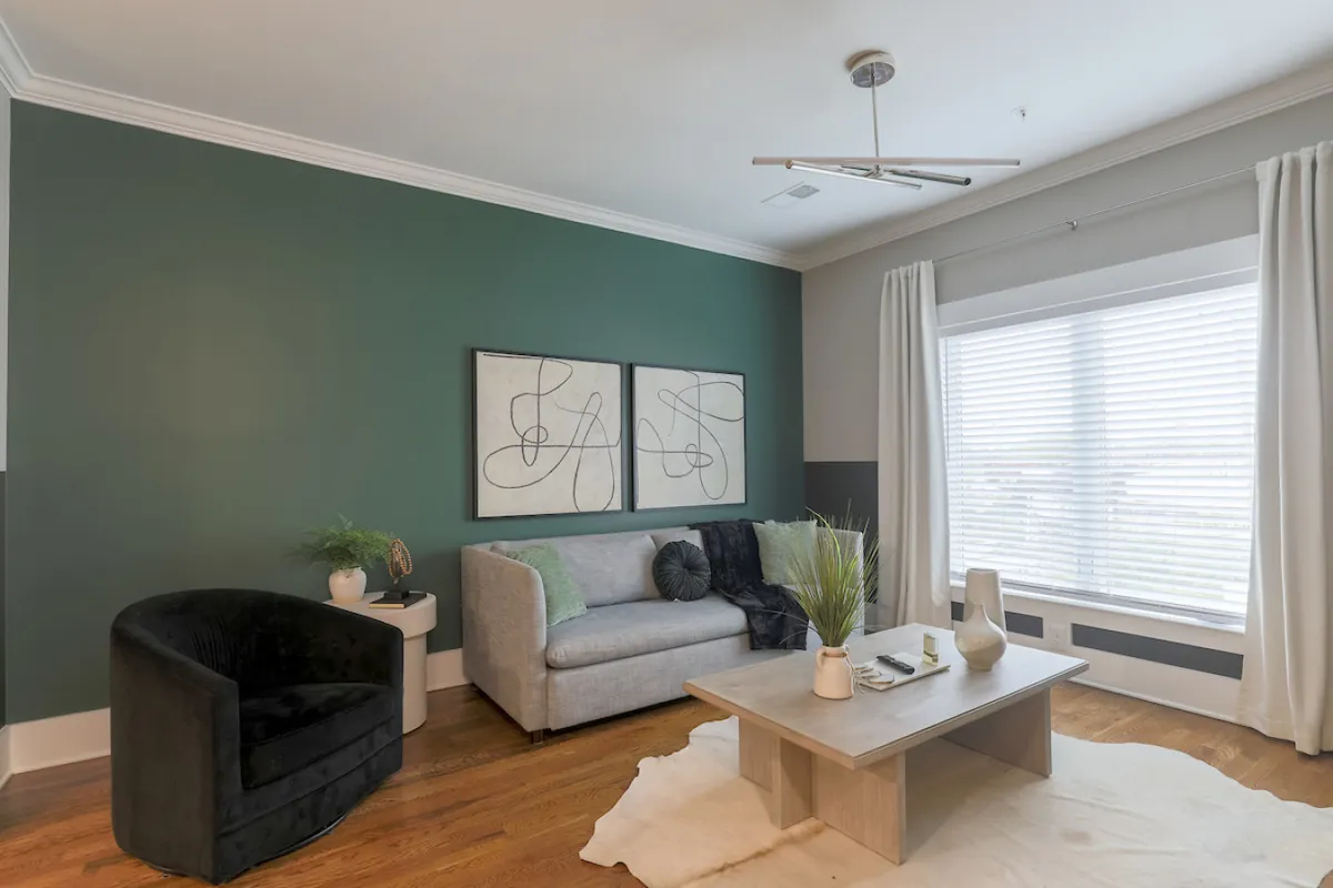 A stylish living area with a comfortable sofa, modern artwork, a coffee table, and a large window. The room is filled with natural light and designed for both socializing and relaxing, ideal for movie nights or quiet mornings.